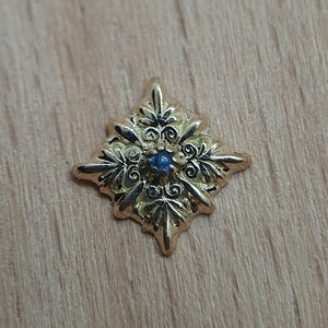 Beautiful ornated threadless piercing attachment in the shape of a snowflake made of 14 karat yellowgold centering a saphire