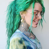 greenhaired woman with tattooed neck and goldtooth wearing seashell earweights