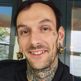 young man with necktattoo smiling wearing earweights in shape of a hannya mask